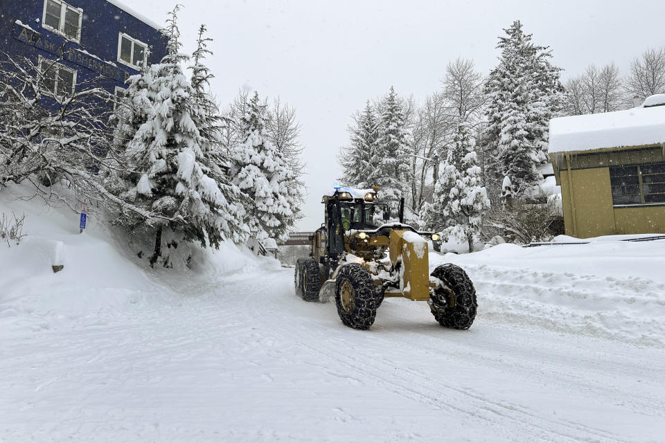 A grader is driven along a downtown street in Juneau, Alaska, on Tuesday, Jan. 23, 2024. Juneau has received more than 55 inches of snow so far in January, far above the normal level of 24.5 inches, according to the National Weather Service. (AP Photo/Becky Bohrer)