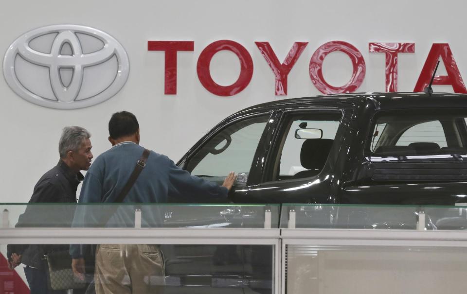 Visitors inspect a car at a Toyota gallery in Tokyo Thursday, May 8, 2014. Toyota's fourth quarter profit dropped slightly despite higher vehicle sales and a weak yen as it spend more on research and development. Toyota Motor Corp. reported Thursday a January-March profit of 297 billion yen ($2.9 billion), down from 313.9 billion yen a year earlier. Quarterly sales rose 12.5 percent to 6.57 trillion yen ($64.5 billion). (AP Photo/Koji Sasahara)