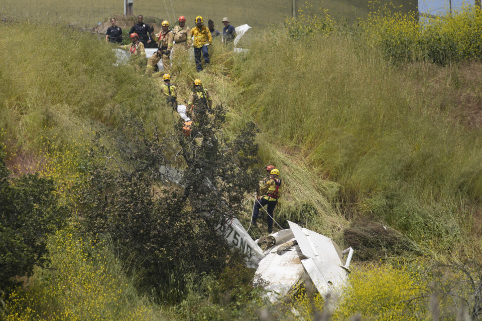 Los Angeles City Fire Department's Urban Search and Rescue members assist in recovering the pilot's body of a downed Cessna C172 on a steep hill above a home on Beverly Glen Circle in Los Angeles, Sunday, April 30, 2023. Fire department officials said a person was found dead following an intensive search for the single-engine airplane that crashed in a foggy area Saturday night. The plane avoided hitting power lines and a large water tank and, officials said, there was minimal fire. (AP Photo/Damian Dovarganes)