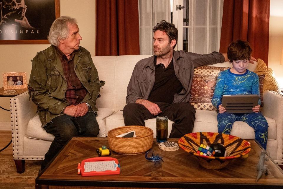 an old man, a middle-aged man, and a child sit on a couch