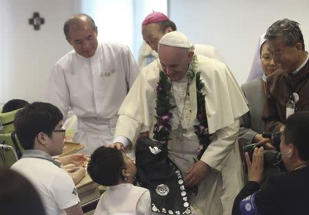 Pope Francis blesses a disabled child during his visit to the rehabilitation center for disabled people at Kkottongnae in Eumseong, August 16, 2014. REUTERS/Ahn Young-joon/Pool