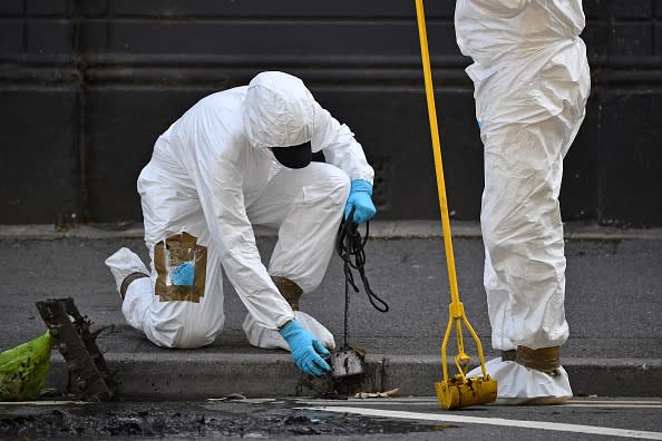 Police forensics officers dressed in Tyvek protective PPE (personal protective equipment) suits and wearing masks, conduct a search of a drain near to Forbury Gardens park in Reading.