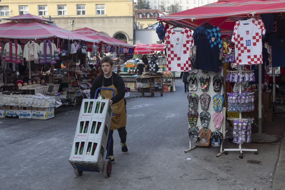 A young man pushes a cart past Croatian national soccer team's jerseys on display at a market ahead of the team's Qatar World Cup soccer semifinal match against Argentina, in Zagreb, Croatia, Tuesday, Dec. 13, 2022. (AP Photo/Marko Drobnjakovic)