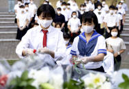 High school students offer flowers for the victims of U.S. atomic bombing in front of a monument at the Atomic Bomb Hypocenter Park in Nagasaki, southern Japan, Sunday, Aug. 9, 2020. Nagasaki marked the 75th anniversary of the atomic bombing on Sunday. (Kyodo News via AP)