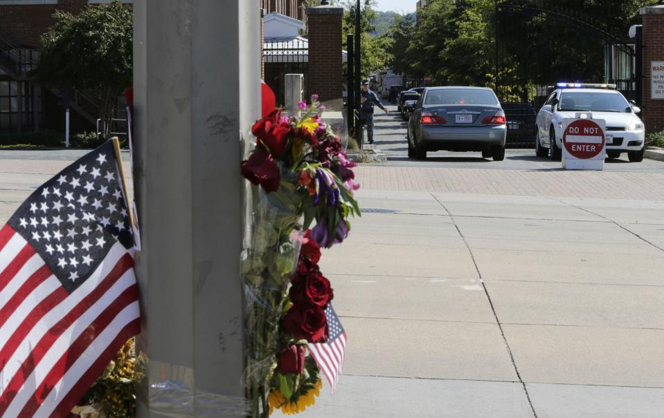 A U.S. flag and flower memorial is shown across the street from the Washington Navy Yard September 19, 2013. Thousands of workers streamed back into the Washington Navy Yard on Thursday, three days after a former reservist working at the site as a contractor opened fire with a shotgun as he wandered several floors and hallways, killing 12 people. REUTERS/Gary Cameron (UNITED STATES - Tags: CIVIL UNREST MILITARY)