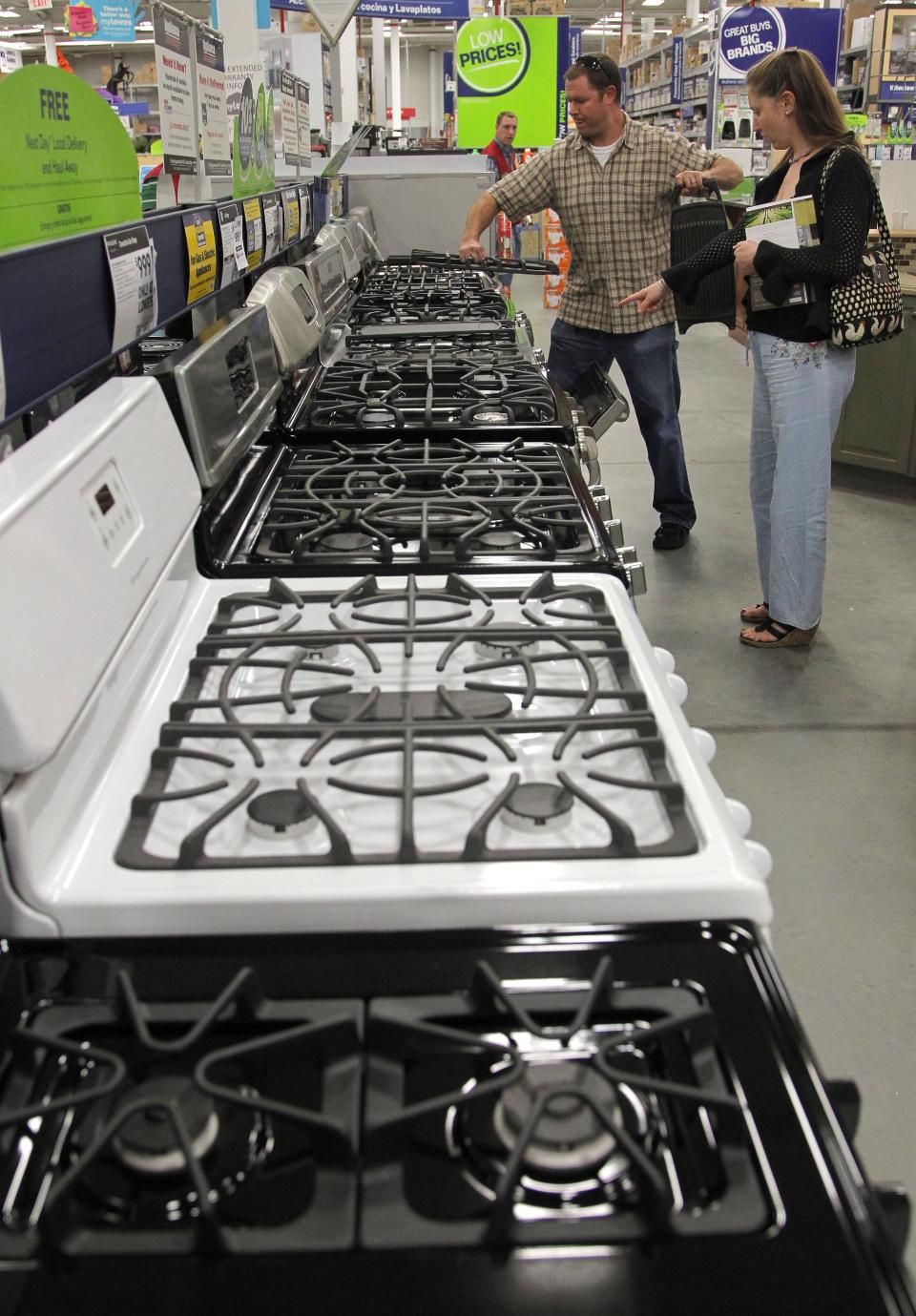 In this Monday, Sept. 10, 2012 photo Brian Gibson, center, and his wife Elizabeth Gibson, right, both of Framingham, Mass., examine stoves at a Lowe's store location in Framingham. U.S. companies remained cautious in September and held back on orders for long-lasting manufactured goods that signal investment plans. (AP Photo/Steven Senne)