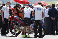 Teammates of 19 years-old Swiss pilot Jason Dupasquier stand near his motorbike as they pay a minute of silence in his memory prior to the start of the Motogp Grand Prix of Italy at the Mugello circuit, in Scarperia, Italy, Sunday, May 30, 2021. Dupasquier died Sunday after being hospitalized Saturday, at the Florence hospital following his crash during the qualifying practices of the Moto3. (AP Photo/Antonio Calanni)