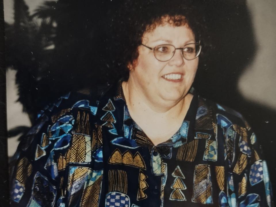 A woman wearing a black, blue and beige patterned shirt.