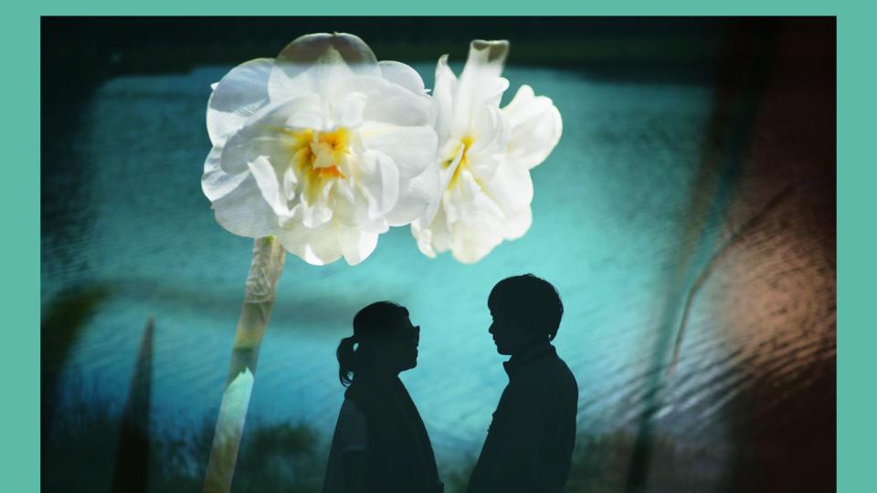 silhouette of two people standing against a mural of white daffodils