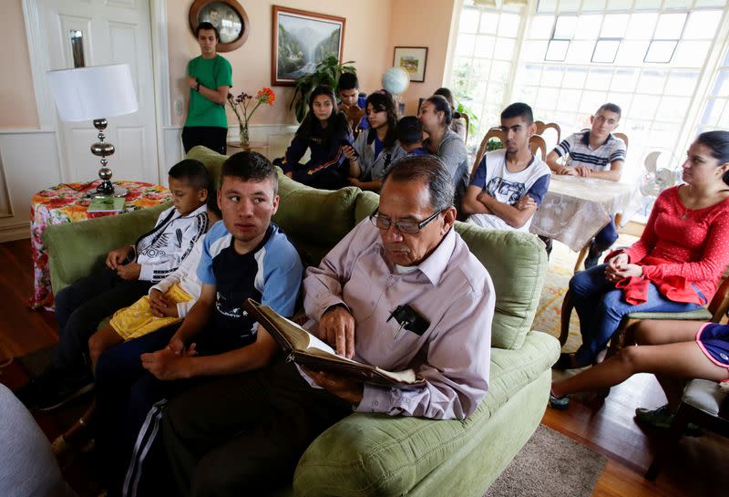 Foto del lunes de Victor Guzman leyendo la Biblia junto a los niños adoptados en su casa en medio de la pandemia de coronavirus en San Jose, Costa Rica
