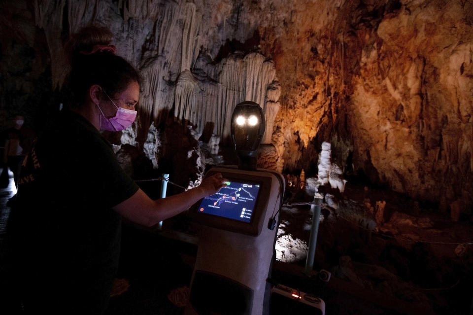 A guide programs Persephone inside Alistrati cave, about 135 kilometers (84 miles) northeast of Thessaloniki, Greece, Monday, Aug. 2, 2021. Persephone, billed as the world's first robot used as a tour guide inside a cave, has been welcoming visitors to the Alistrati cave, since mid-July. (AP Photo/Giannis Papanikos)