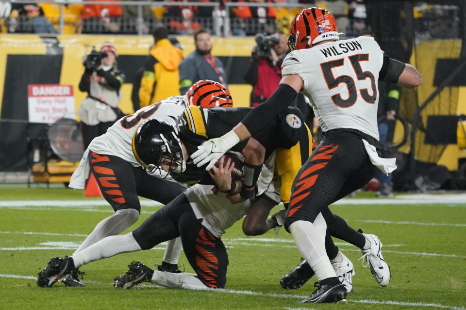 Pittsburgh Steelers quarterback Mason Rudolph rushes for a first down as he is tackled by, from left, Cincinnati Bengals safety Nick Scott, cornerback Mike Hilton, and linebacker Logan Wilson during the first half of an NFL football game Saturday, Dec. 23, 2023, in Pittsburgh. (AP Photo/Gene J. Puskar)