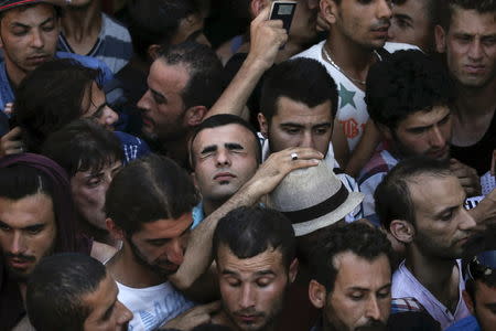 A Syrian refugee tries to catch his breath as he stands in a crowded line to get registered in the national stadium of the Greek island of Kos, August 12, 2015. REUTERS/Alkis Konstantinidis