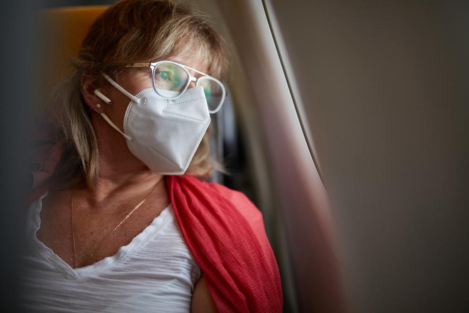 Middle-age Traveler in KN95 Mask Looking Out Airplane Window