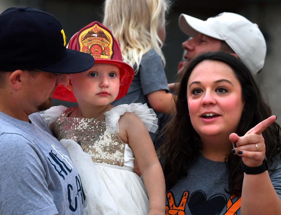 Tony and Danielle Molina hold their daughter Sienna as they watch a parade go past their driveway Tuesday.