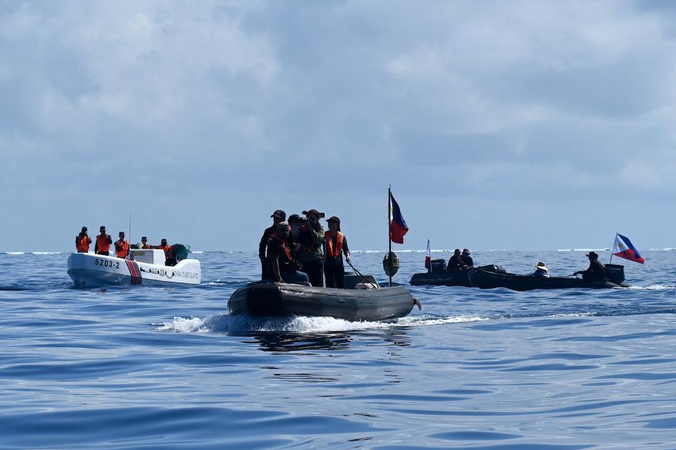 Two Inflatable boats with the Philippine flag are stopped by a white Chinese Coast Guard boat.