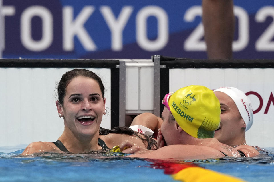 Kaylee McKeown, left, of Australia is congratulated by compatriot Emily Seebohm and Canada's Kylie Masse, right, after winning the final of the women's 100-meter backstroke at the 2020 Summer Olympics, Tuesday, July 27, 2021, in Tokyo, Japan. (AP Photo/Matthias Schrader)