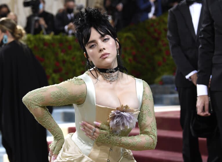 A woman with black hair poses in an old-fashioned corset dress