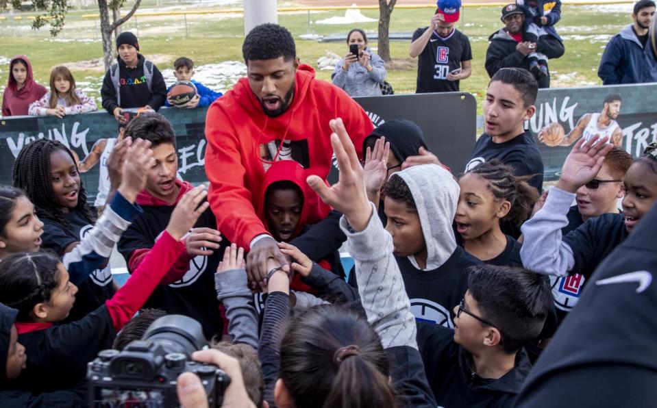 Clippers forward Paul George greets young fans on a park basketball court.