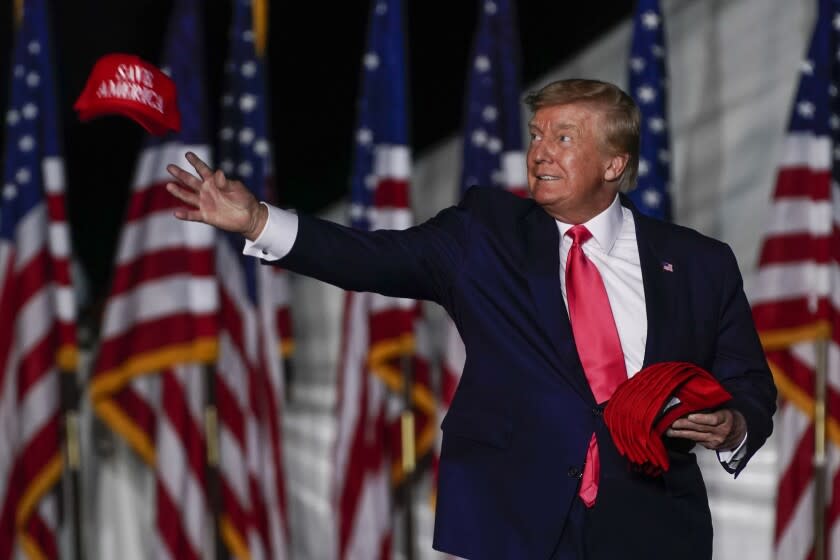 El expresidente Donald Trump lanza gorras al público al llegar a un mitin el viernes 5 de agosto de 2022, en Waukesha, Wisconsin (AP Foto/Morry Gash)