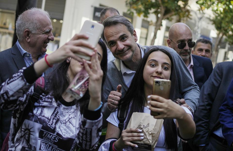 Greece's Prime Minister and New Democracy leader Kyriakos Mitsotakis takes selfies with teenagers during his election campaign in Livadia town about 143 kilometers (89 miles) north of Athens, Greece, Tuesday, April 25, 2023. (AP Photo/Thanassis Stavrakis)