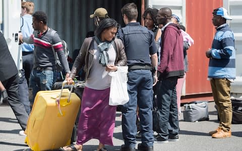 Asylum seekers unload their belongings from a truck at a processing centre near the Canada-United States border in Lacolle, Quebec - Credit: Graham Hughes/The Canadian Press via AP