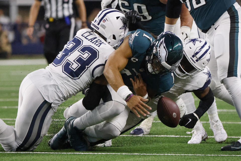 Dallas Cowboys safety Donovan Wilson, right, forces a fumble by Philadelphia Eagles quarterback Jalen Hurts, center, as teammate Damone Clark (33) helps apply pressure during the first half of an NFL football game, Sunday, Dec. 10, 2023, in Arlington, Texas. The Cowboys recovered the ball on the play. (AP Photo/Michael Ainsworth)