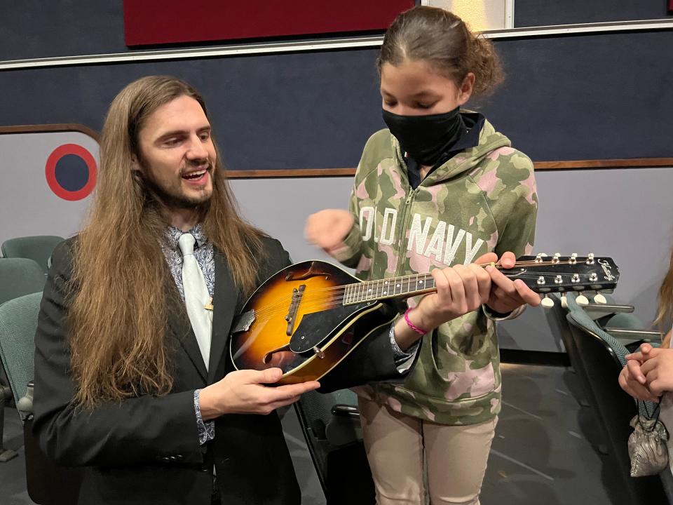 Jake Howard shows Makayah Hart how to play the mandolin.