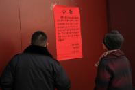 People look at a notice at the gate of the Lama Temple saying that the temple is closed for the safety concern following the outbreak of a new coronavirus, in Beijing