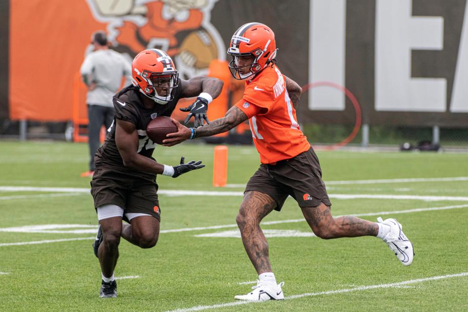 Running back Hassan Hall, left, takes a handoff from quarterback Dorian Thompson-Robinson, right, during Browns rookie minicamp in Berea, Friday, May 12, 2023.