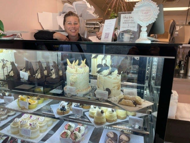 The Chocolate Rose Bakery owner Vanessa Benoit stands behind the cake case, with individual servings on the shelf below. The Rose, located in Mashpee and named after Benoit's grandmother, was voted Best Bakery on Cape Cod by readers.