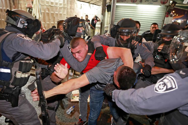 Las fuerzas de seguridad israelíes impiden que los manifestantes palestinos se apoderen de su arma fuera de la Puerta de Damasco en la Ciudad Vieja de Jerusalén el 9 de mayo de 2021. Israel prometió restaurar el orden en Jerusalén después de que cientos de manifestantes palestinos resultaron heridos en un fin de semana de enfrentamientos con las fuerzas de seguridad israelíes, como Se pospuso una audiencia judicial clave sobre una disputa de propiedad en un punto álgido