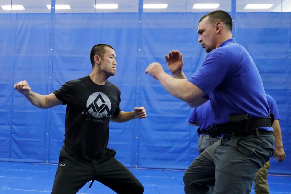 In this June 4, 2020, photo, Brandon Wilson, right, an instructor at the Washington State Criminal Justice Training Commission facility in Burien, Washington, defends against a simulated punch thrown by fellow instructor Ben Jia during a demonstration for The Associated Press on takedown and restraint techniques taught to law enforcement officers.