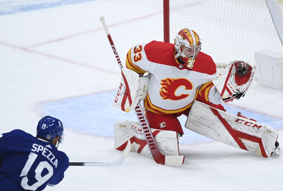 Calgary Flames goaltender David Rittich (33) makes a glove-save against Toronto Maple Leafs center Jason Spezza (19) during second-period NHL hockey game action in Toronto, Monday, Feb. 22, 2021. (Nathan Denette/The Canadian Press via AP)