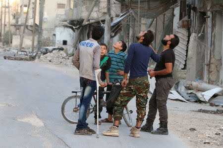 People look at the sky fearing an airstrike in the rebel-held al-Myassar neighborhood of Aleppo, Syria. REUTERS/Abdalrhman Ismail