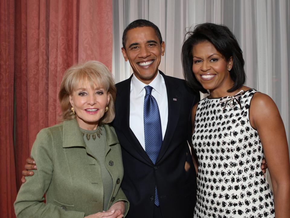 A woman with blonde hair and a green suit stands next to a man with a black suit and a woman with a black and white dress