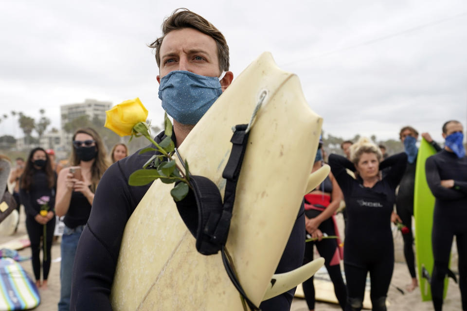 Robert Huffman holds his surfboard and a rose as he participates in a paddle out ceremony at "The Ink Well," a beach historically known as a surfing refuge for African Americans, to honor the life of George Floyd on Friday, June 5, 2020, in Santa Monica, Calif. Floyd died after he was restrained in police custody on Memorial Day in Minneapolis. (AP Photo/Ashley Landis)