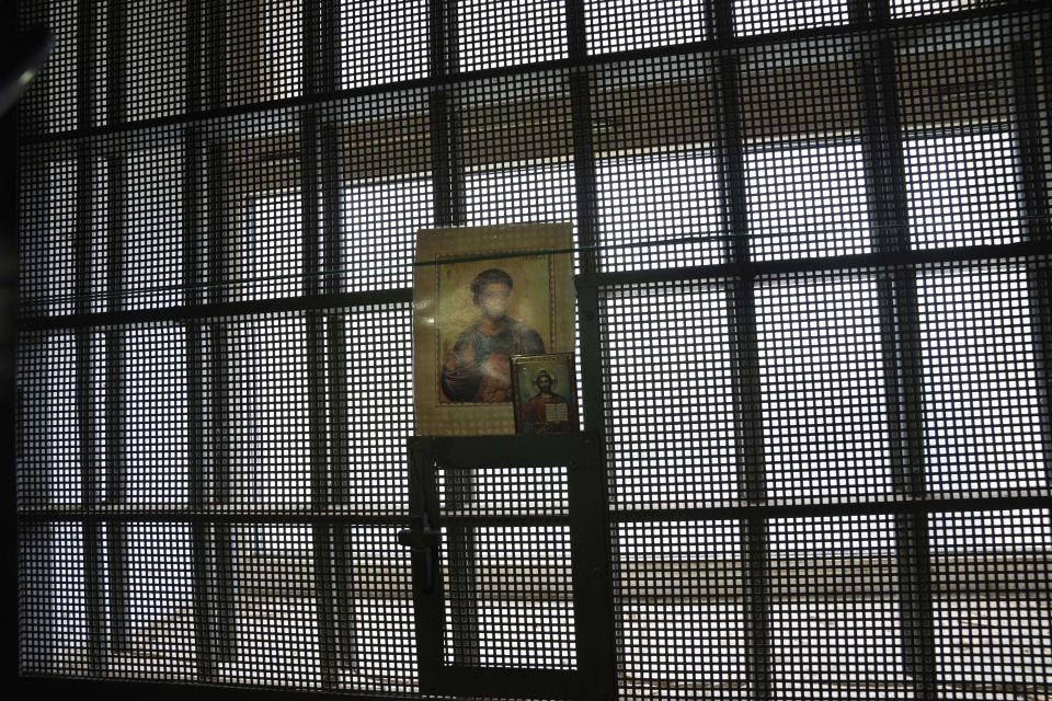 Religious icons hang from bars on a window inside a building in which Ukrainian civilians said they were detained and tortured during the Russian occupation of Kherson, Ukraine, Thursday, Dec. 8, 2022. Many civilians described how having images of icons in their cells helped them endure the ordeal. (AP Photo/Evgeniy Maloletka)