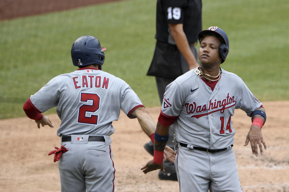 Washington Nationals' Starlin Castro (14) celebrates with Adam Eaton (2) after both scored on a double by Kurt Suzuki during the third inning of the team's baseball game against the Toronto Blue Jays, Thursday, July 30, 2020, in Washington. (AP Photo/Nick Wass)