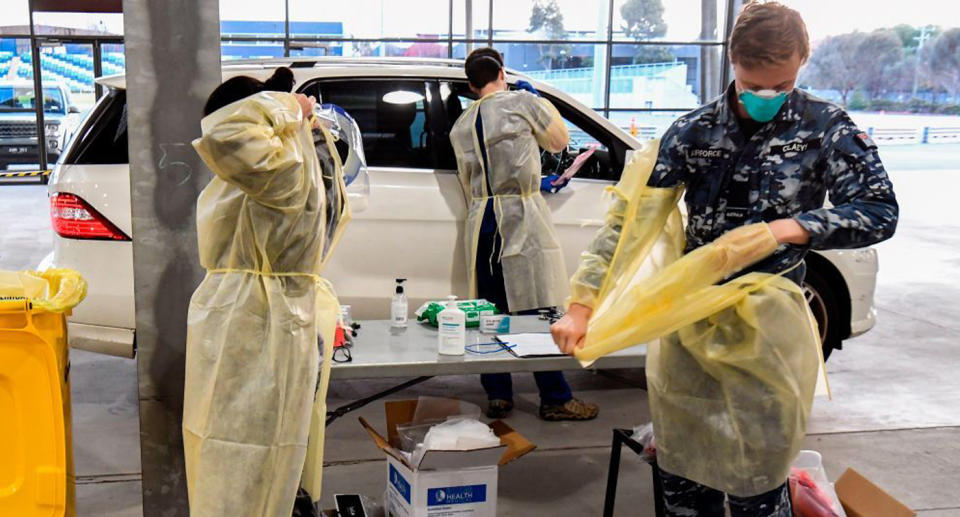 An Australian Defence Force member and two other healthcare workers in PPE at a Melbourne coronavirus test station.