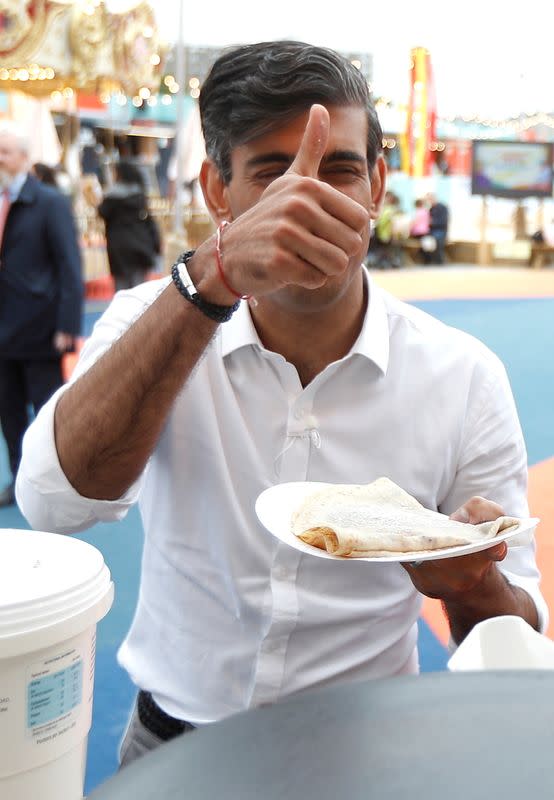 FILE PHOTO: Britain’s Chancellor Rishi Sunak gestures as he takes a pancake from a stall at the London Wonderground comedy and music festival venue in London