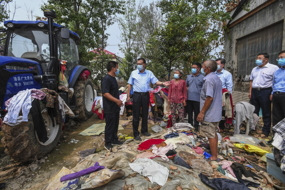 In this Aug. 18, 2021, photo released by Xinhua News Agency, Chinese Premier Li Keqiang, center, wearing a face mask, talks to residents as he visits the flood hit area in Zhengzhou city in central China's Henan province. Li vowed to hold officials accountable over mistakes during recent floods that led to the deaths of hundreds of people in a major provincial capital, including 14 who were trapped when the city’s subway system was inundated. (Rao Aimin/Xinhua via AP)