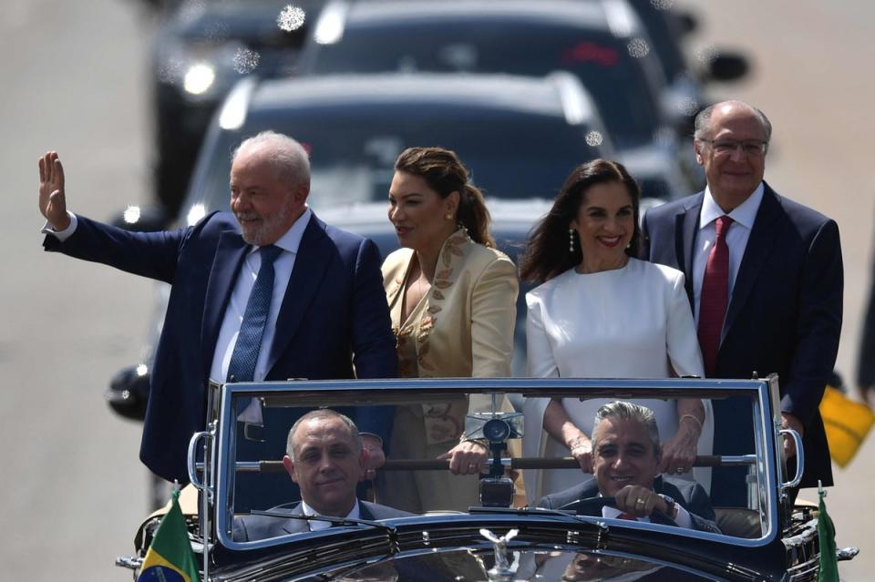 Lula (L) waves to supporters, accompanied by his wife Rosangela da Silva (2-L), his Vice-President-elect Geraldo Alckmin (R), and his wife, Maria Lucia Ribeiro Alckmin, on their way to the inauguration ceremony (AFP via Getty Images)