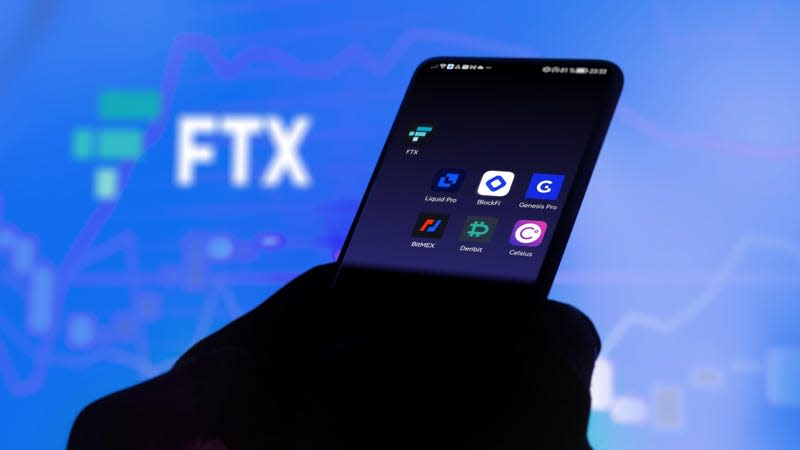 A phone with a screen bearing icons for FTX, blockfi, Genesis, Bitmex, deribit, and celcius in front of screen with the FTX logo