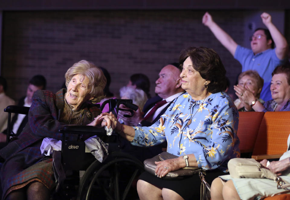 Aranka Engel, 103, left, holds the hand of fellow Holocaust survivor Jean Kurz, 81, while watching Orthodox Jewish singer Yaakov Shwekey perform at a concert honoring them and dozens of other Holocaust survivors on Monday, June 14, 2021, at the Yeshivah of Flatbush theater at Joel Braverman High School in the Brooklyn borough of New York. It was the first large gathering for New York-area Holocaust survivors after more than a year of isolation due to the coronavirus pandemic. (AP Photo/Jessie Wardarski)