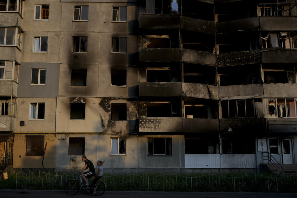 A man rides a bicycle past a building destroyed in Russian attacks in Borodyanka, on the outskirts of Kyiv, Ukraine, Sunday, June 12, 2022. (AP Photo/Natacha Pisarenko)