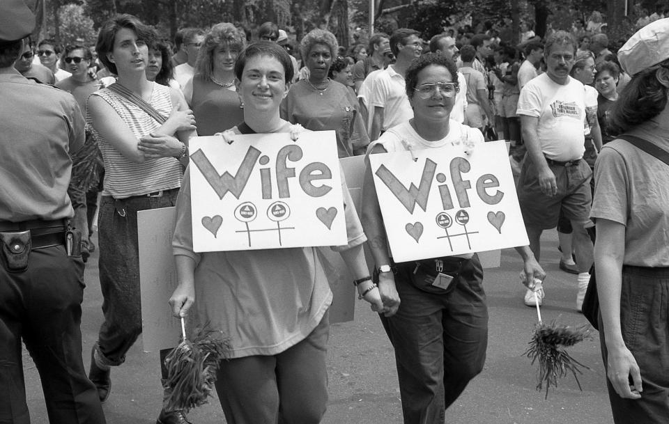 Two women wearing 'Wife' signs around their necks, smile for the camera, at the 1989 gay Pride parade in Greenwich Village, Manhattan, commemorating the 20th anniversary of the Stonewall Riots, June 25, 1989:&nbsp;