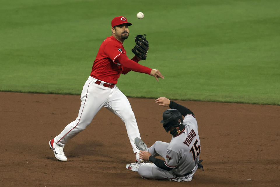 Cincinnati Reds' Eugenio Suarez, left, throws to first to turn a double play as Arizona Diamondbacks' Andrew Young, right, is forced out at second base during the sixth inning of a baseball game in Cincinnati, Wednesday, April 21, 2021. (AP Photo/Aaron Doster)