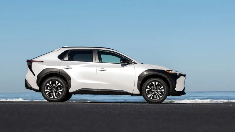 A white Toyota bZ4X EV seen in profile near a shoreline.