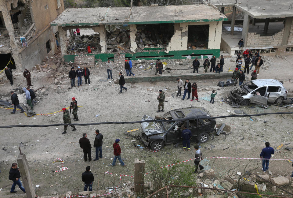 Security personnel and onlookers gather at the site of a deadly car bombing Sunday night, in the town of Nabi Othman, about 30 kilometers (18 miles) north of Baalbek, northeast Lebanon, Monday, March 17, 2014. Lebanese security officials said the explosion killed at least two people and caused panic and massive destruction in the Hezbollah stronghold, which has a sizable Christian population in addition to Shiites. The civil war in neighboring Syria already has ignited polarizing sectarian tensions between Lebanon's Sunnis and Shiites. (AP Photo/Hussein Malla)